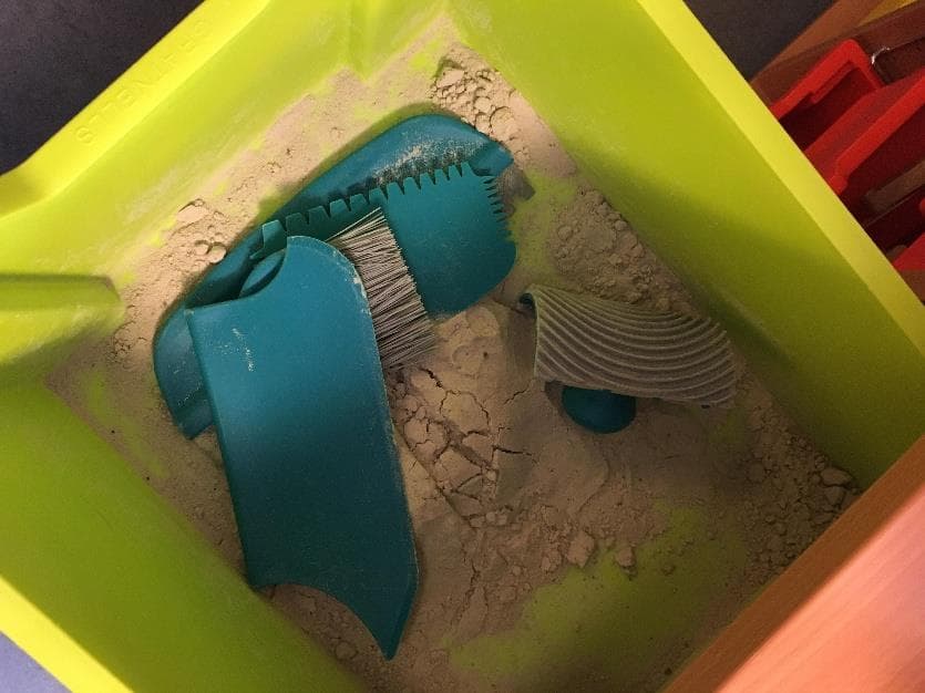 Kinetic-Sand und Formen in einer grünen Materialkiste